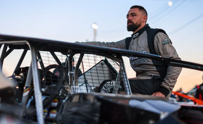 Racer standing beside dirt track car