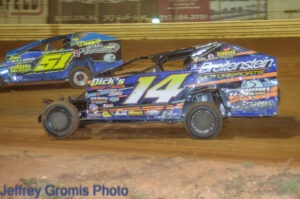 Two dirt modifieds racing side-by-side