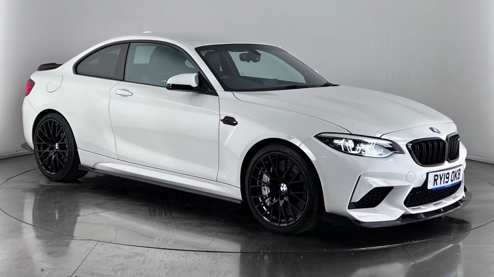 White BMW M2 Competition against gray wall