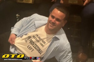 Man holds sign at dirt track