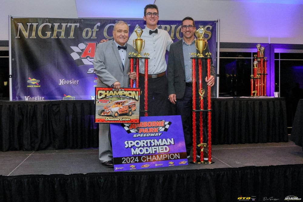 Three racers holding victory trophies