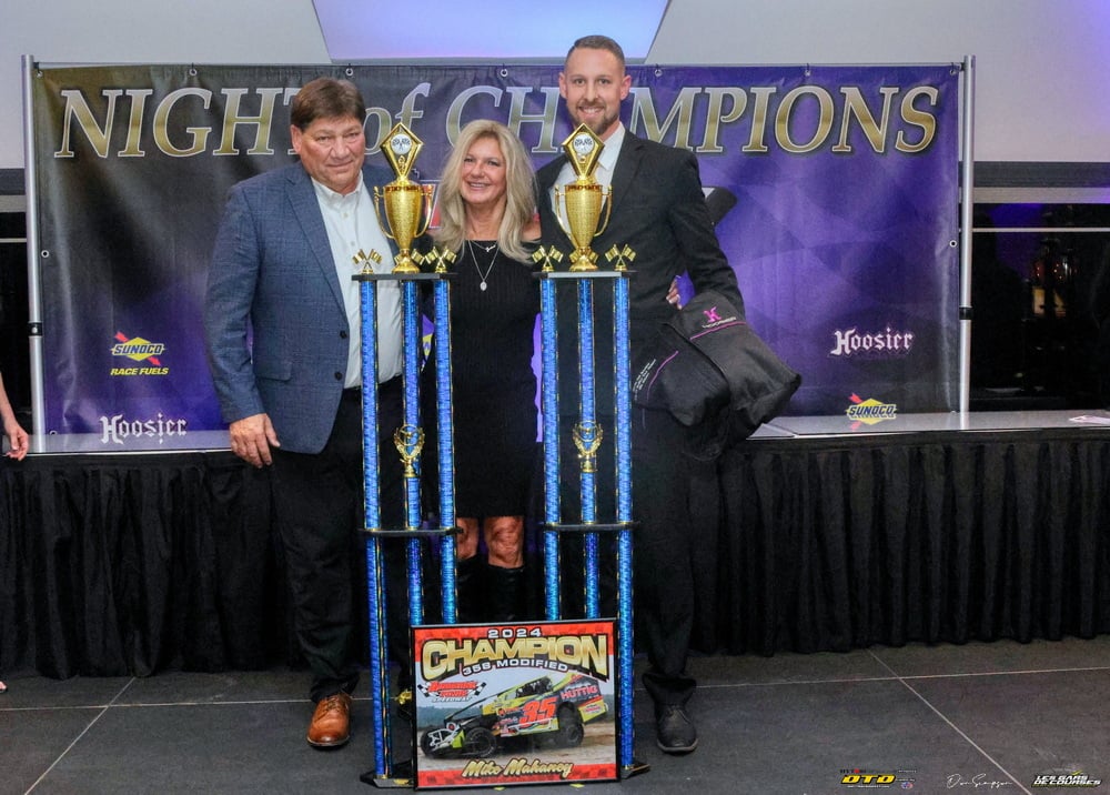 Three racers celebrate with trophy