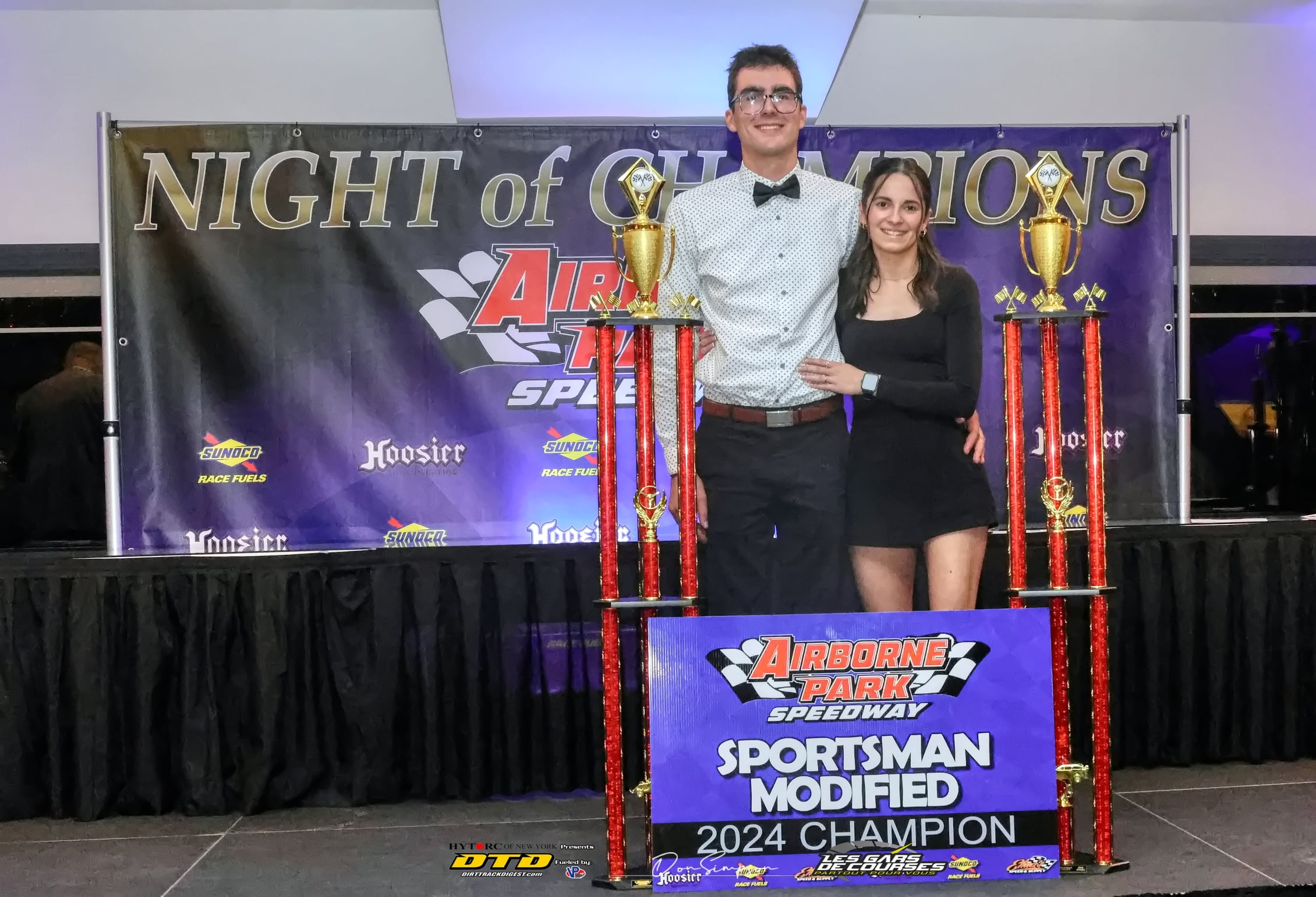 Two racers holding racing trophies