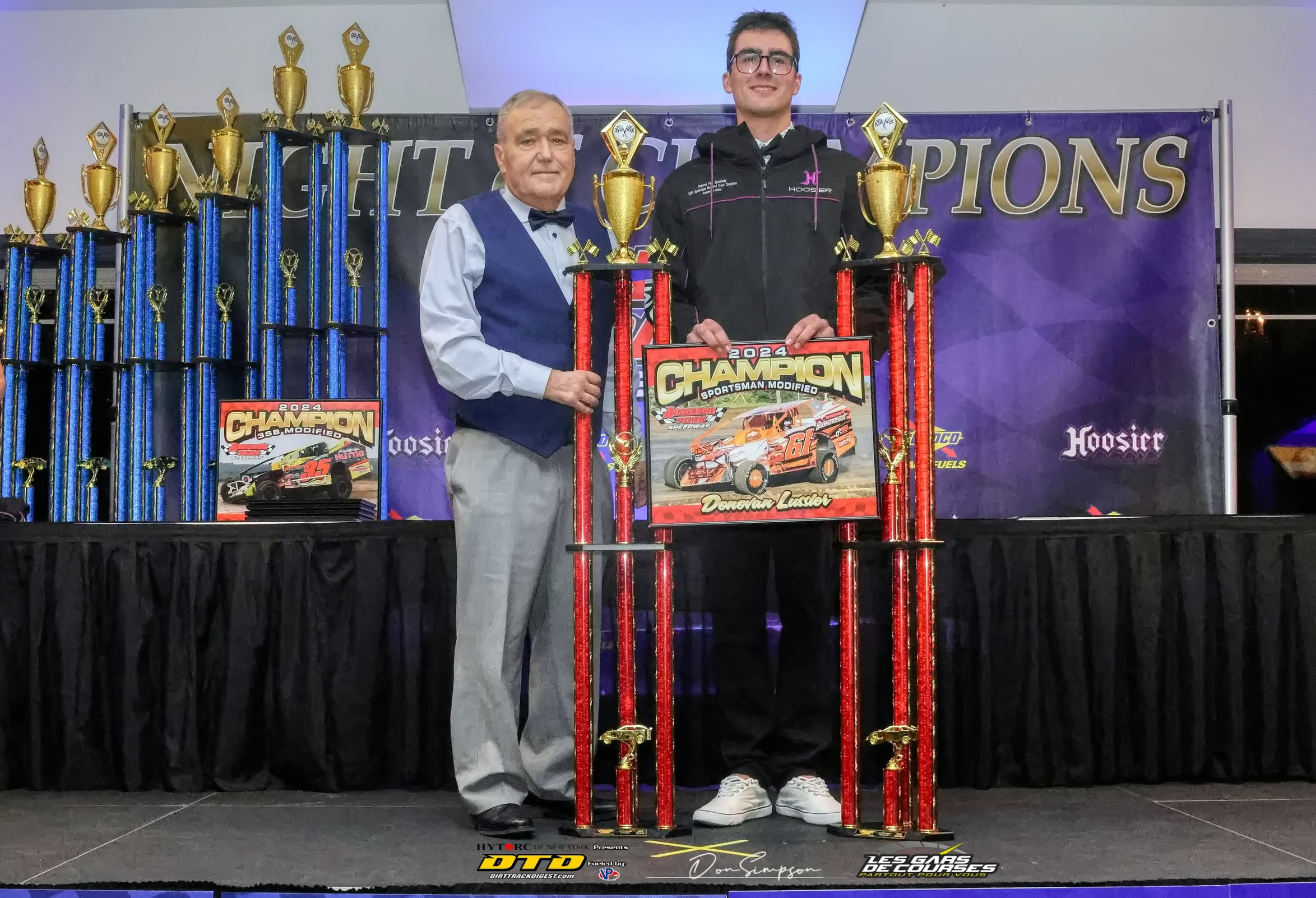 Two men holding racing trophies onstage