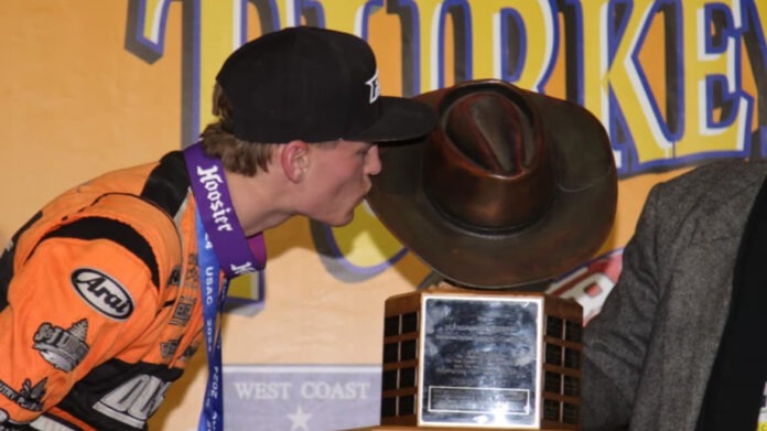 Man kissing dirt track race trophy