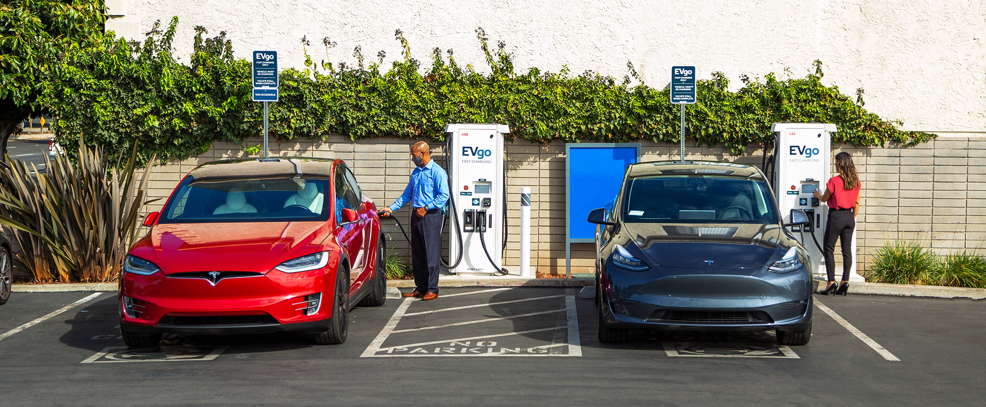 Two people charging electric vehicles