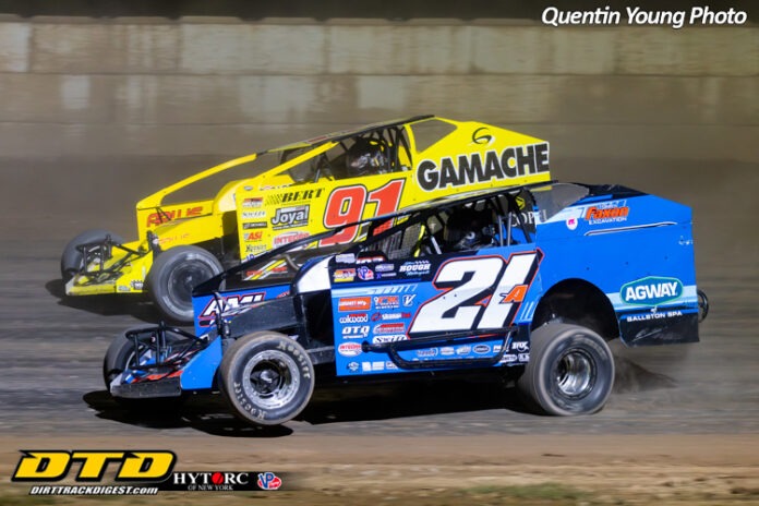 Two race cars compete on dirt