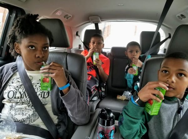 Children drinking water in backseat