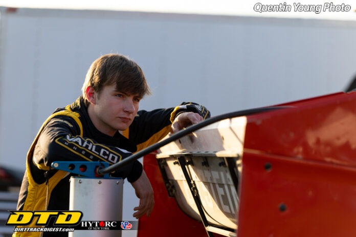 Racer leaning on dirt track car