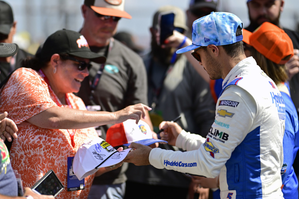 Man autographing white baseball cap