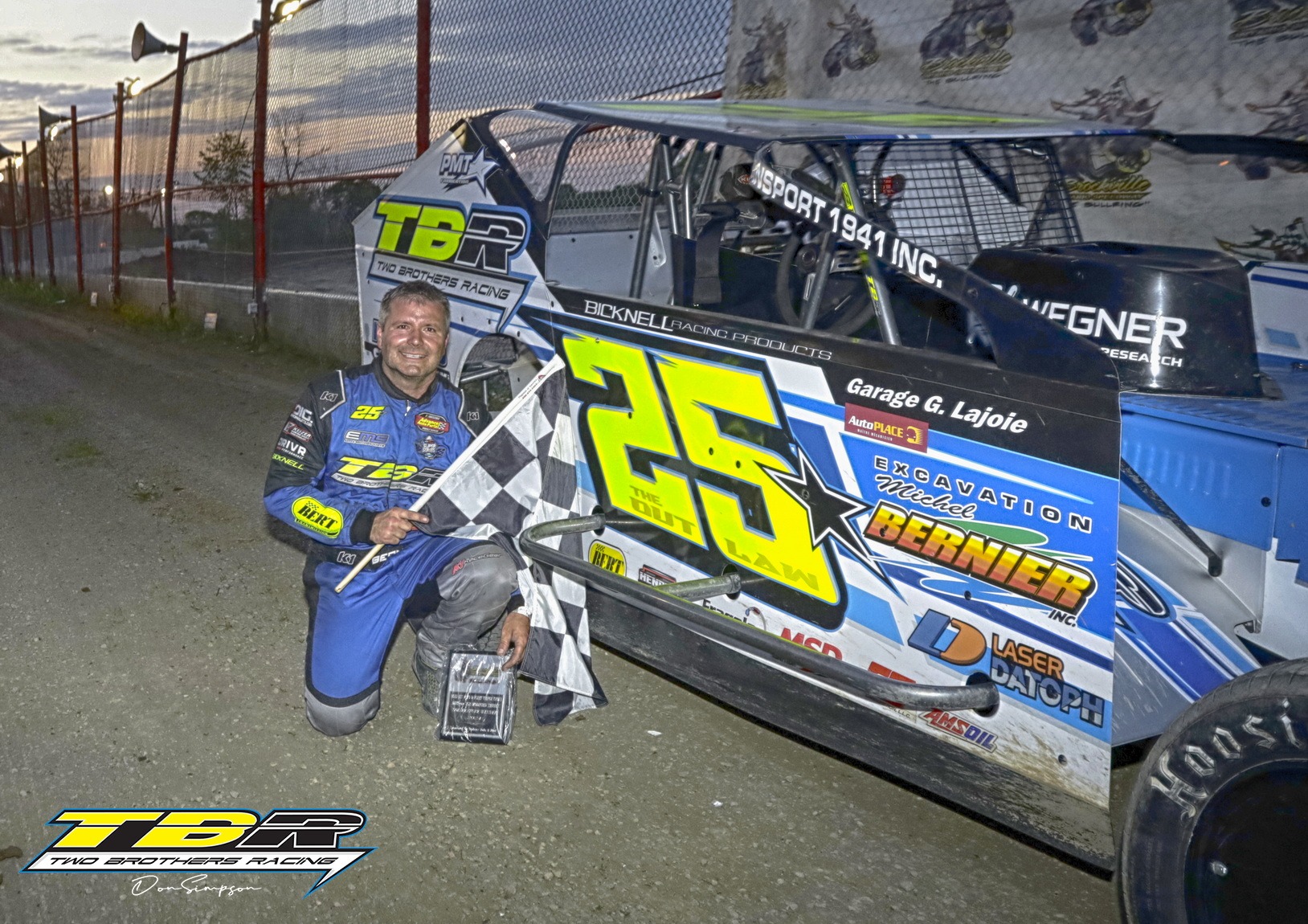 Driver kneeling beside dirt track car