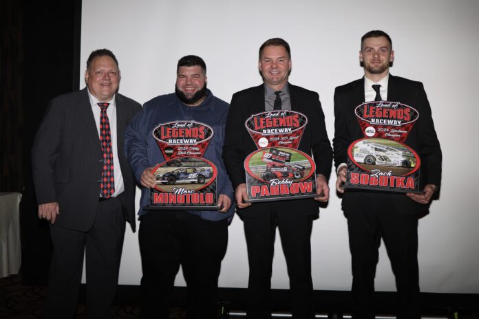 Four men display racing awards