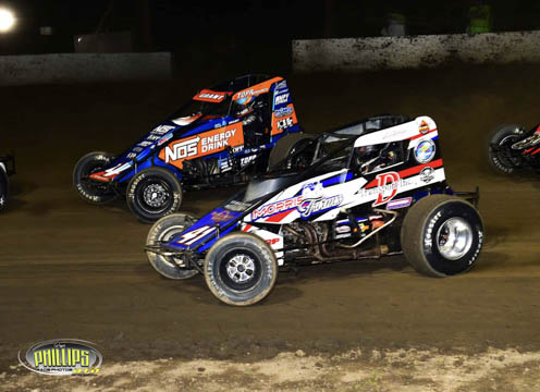 Two sprint cars racing on dirt