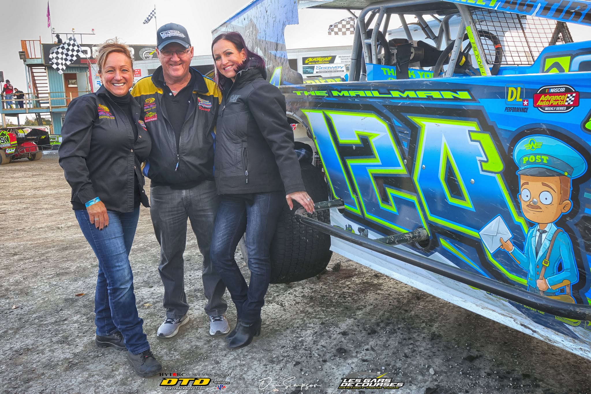 Three people pose by racing car