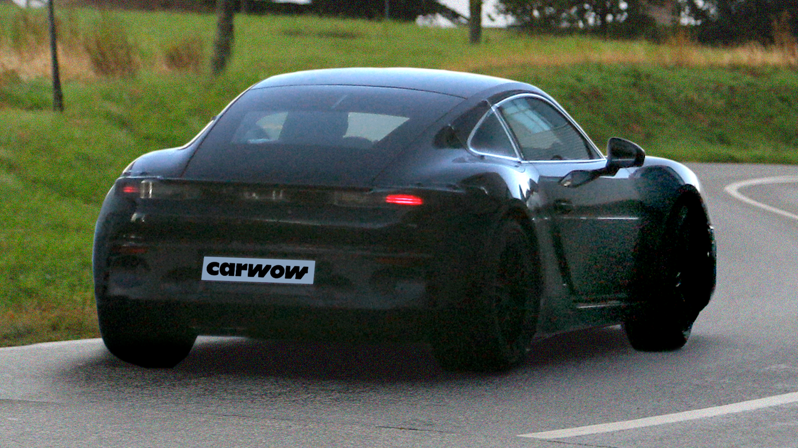 Black Porsche Cayman driving on road