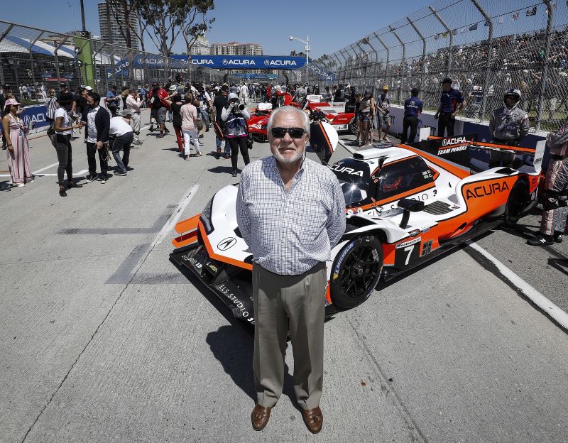 Senior man beside IndyCar racing vehicle