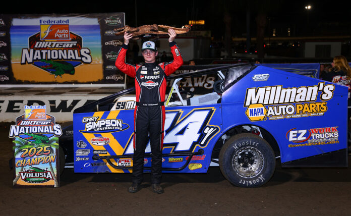 Champion holding trophy over race car