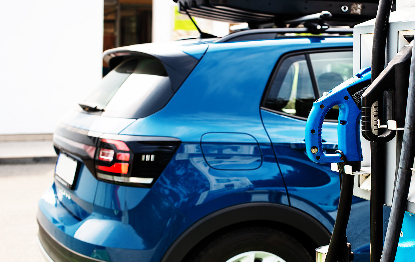 Blue car charging at gas station