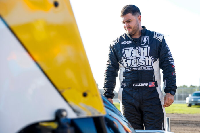 Racecar driver beside dirt track vehicle