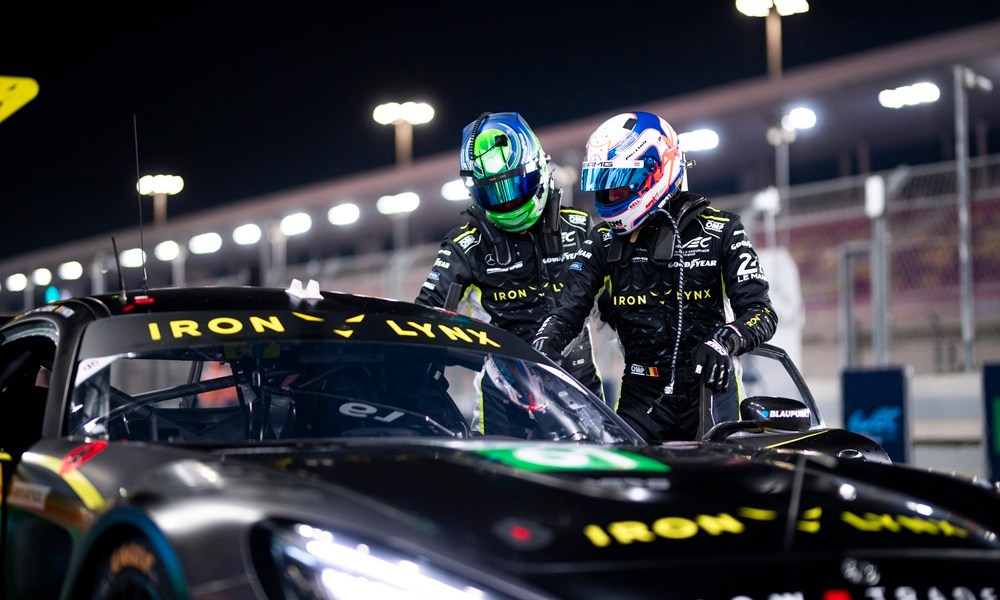 Two helmeted racers in conversation